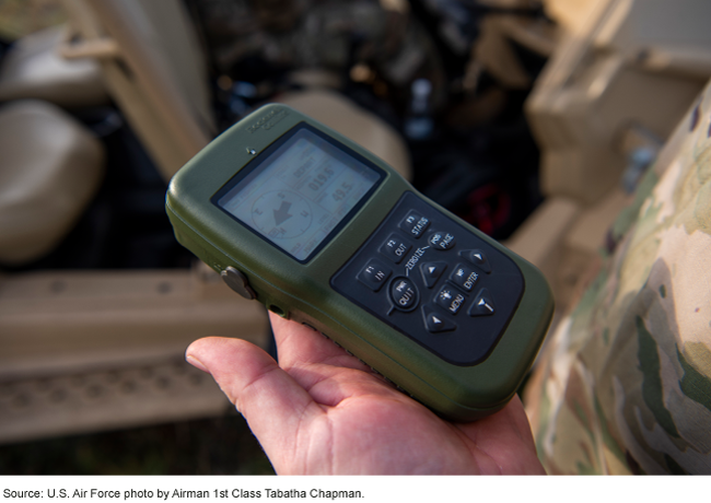 Photo showing a military service member in fatigues holding a GPS device. 