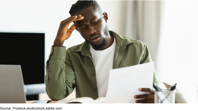 A person sitting at a desk reading a piece of paper