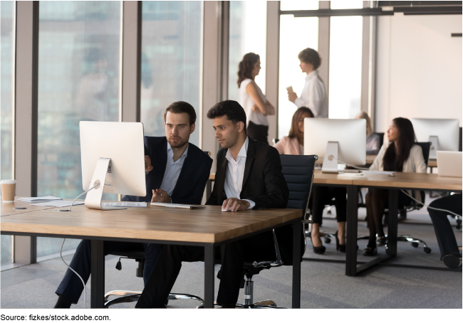 People in business attire sitting at desks with computers.