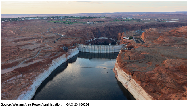 aerial view of a concrete-arch dam with a bridge in the background