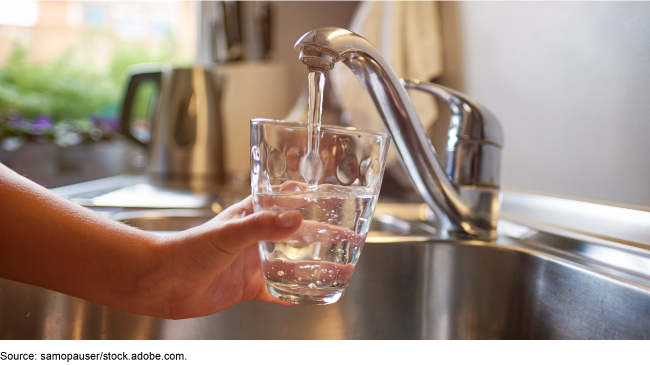 A person filling up a glass of water