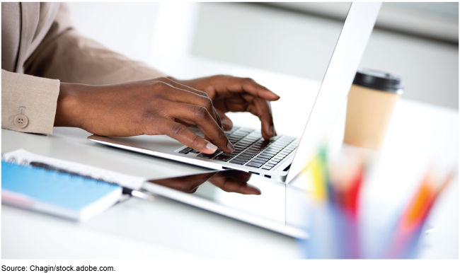 A woman's hands typing on a laptop