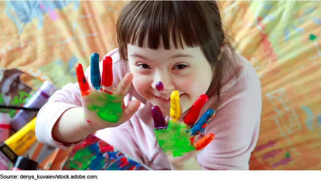 Photo showing a young child playing with finger paints.