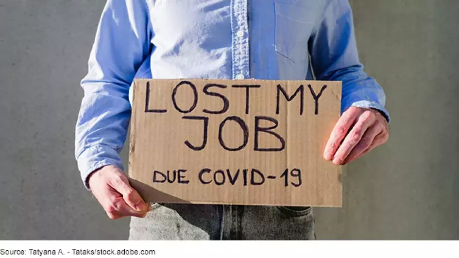 Photo (staged) of a man holding a cardboard sign that says he lost his job due to COVID-19