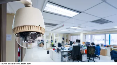 Stock image showing a camera mounted near the ceiling in an office space.