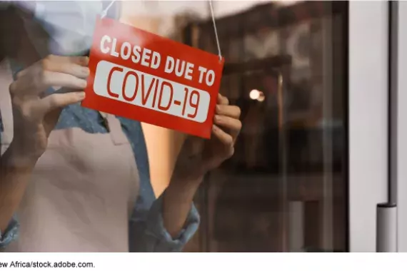 Photo of a &quot;Closed for COVID&quot; sign in a business window
